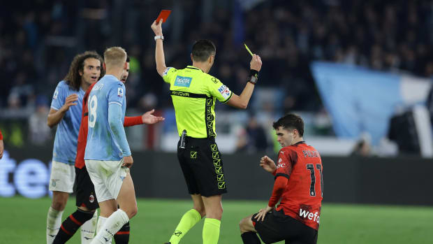 Referee Marco Di Bello pictured showing a red card to Lazio midfielder Matteo Guendouzi (left) and a yellow card to AC Milan forward Christian Pulisic (right) during a Serie A game in March 2024